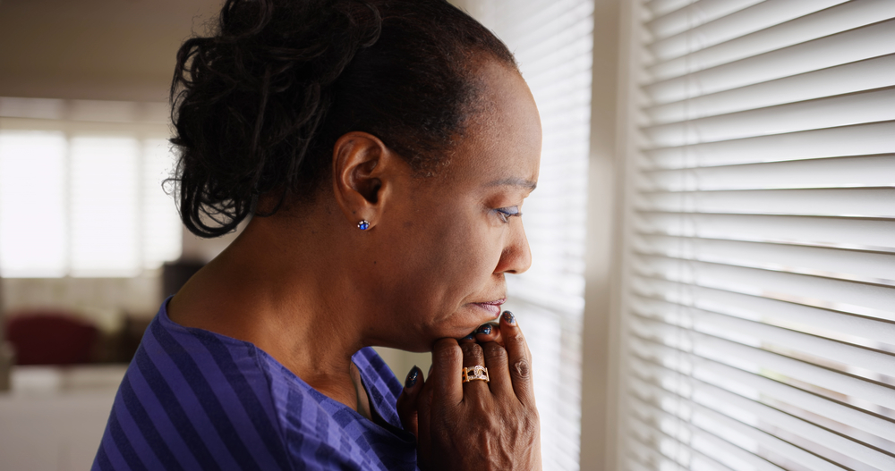 Alt text: racism: An older black woman mournfully looks out her window