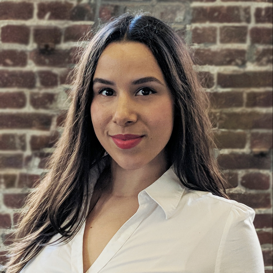 Martha Ockenfels-Martinez (headshot), research associate at Human Impact Partners, smiling woman with long brown hair, lipstick, white shirt.