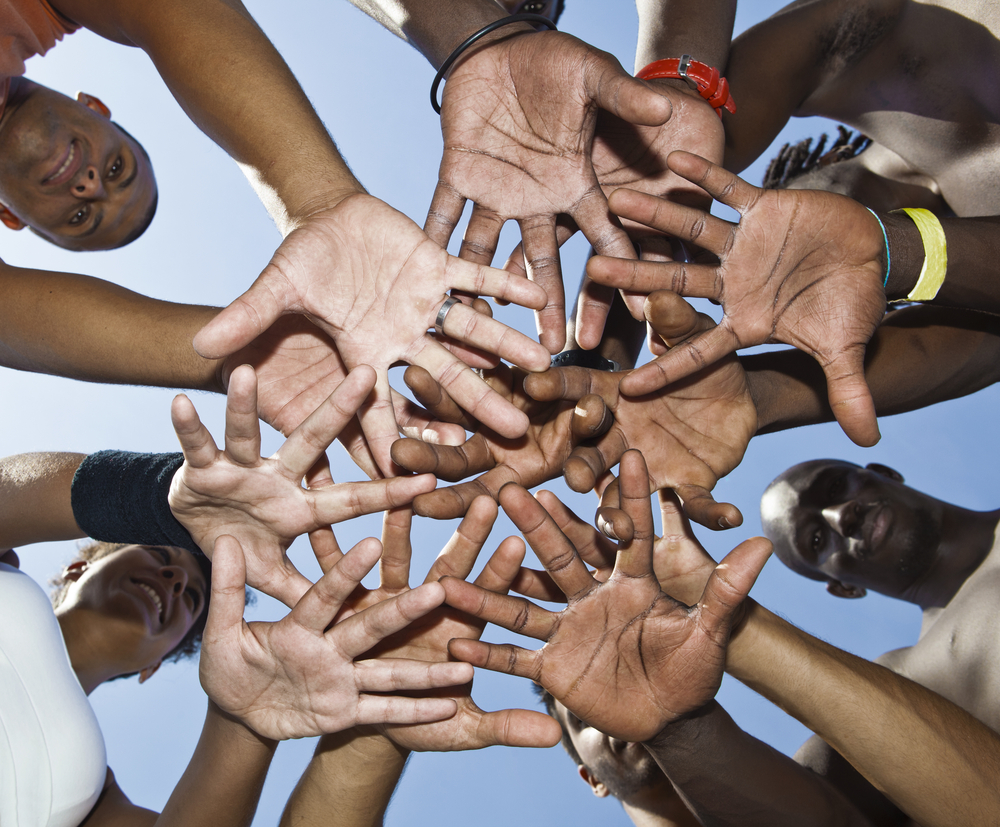 Oakland: A group of mixed race people putting hands together