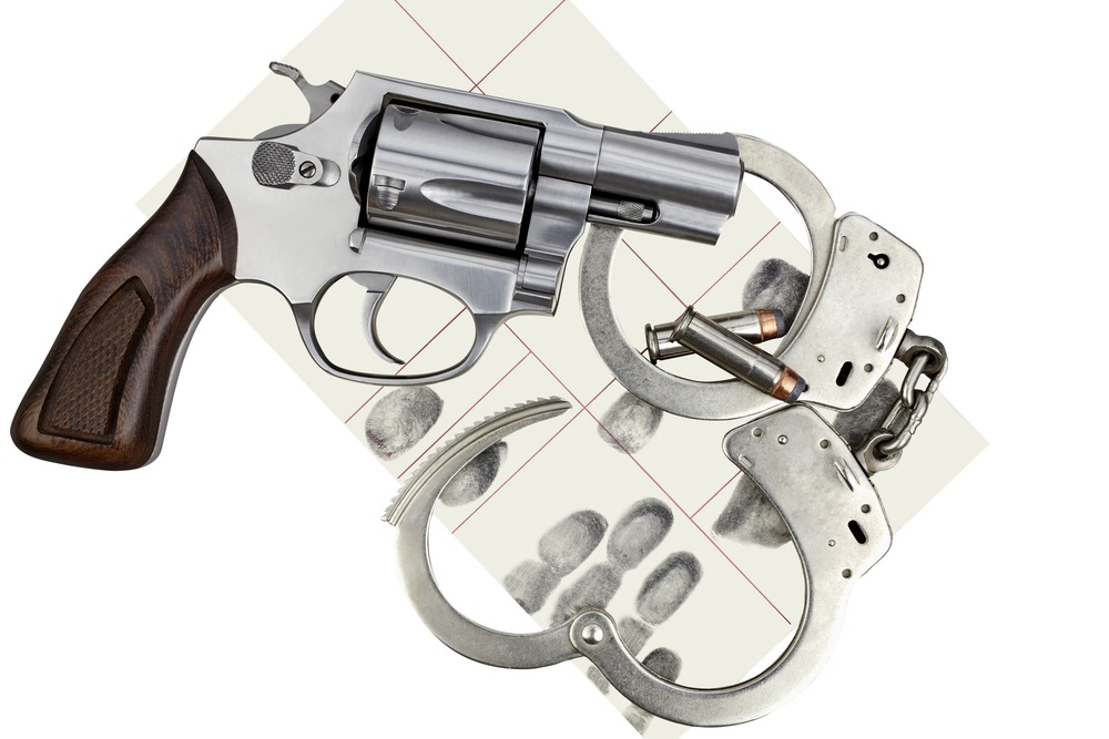gun violence: Gun with handcuffs and fingerprint ID for criminal arrest.