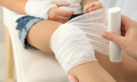 camp: Woman winding bandage around little girl's knee.