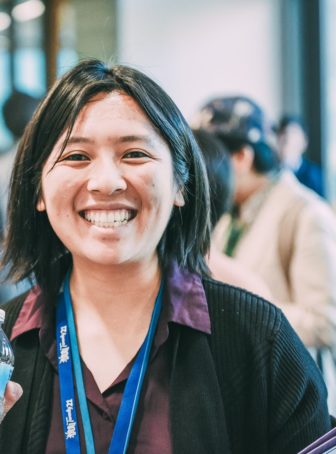 after-school: Diane Hsieh (headshot), third-year Ph.D. student in University of California, Irvine School of Education, smiling young woman with shoulder-length black hair, black sweater, purple shirt, lanyards