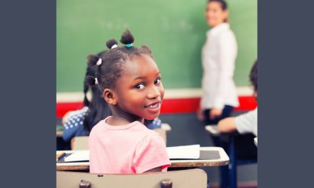 $23 billion education racial disparity report; young black girl in classroom looking back at camera