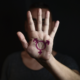 transgender youth, high school youth report; young man holding hand to camera with transgender symbol on it