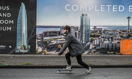Man skateboards past billboards about new condos.