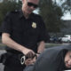 Police officer arresting man, putting him on side of car.