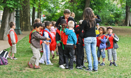 Group of unidentified kids with two teachers in the city park.