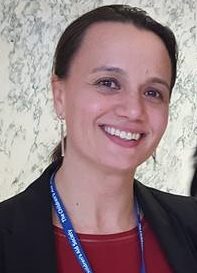  Jill Bloch (headshot), New York director for iFoster, smiling woman wearing earrings, lanyard, dark jacket, red top.