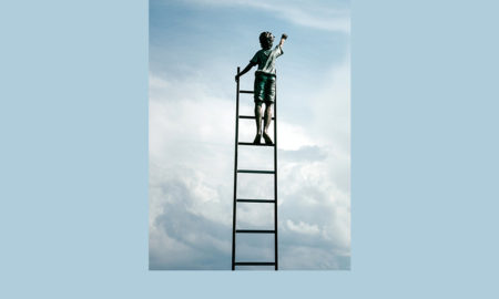 Boy on ladder leaning on nothing reaching into clouds.