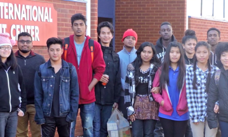 robotics: Students stand as group outside brick building.