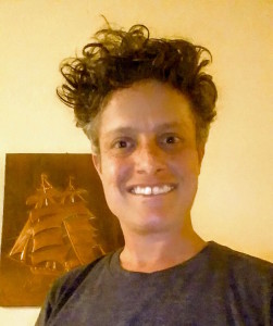 LGBTQ: Smiling woman with short curly hair, gray top.