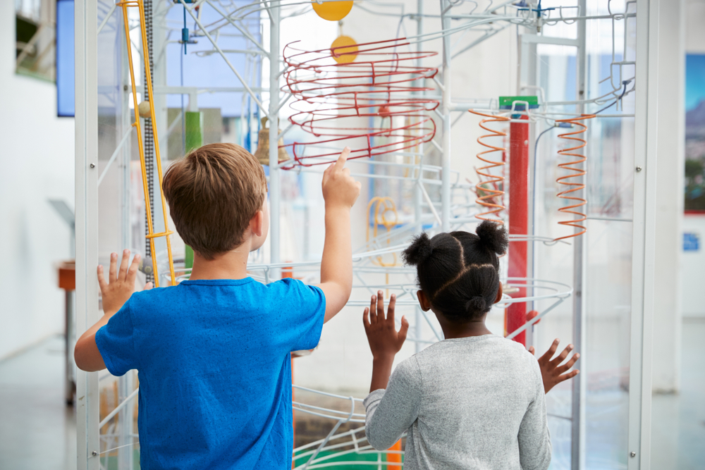 summer learning: Two kids looking at a science exhibit, back view
