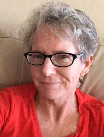 restorative justice: Jean Campbell (headshot), freelance writer, freckled woman with short gray hair, glasses, orange top.