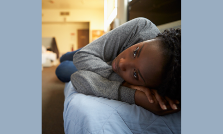 homeless youth housing grants; young african american woman laying on bed in shelter