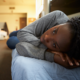 homeless youth housing grants; young african american woman laying on bed in shelter