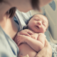 new-born child health project grants; mother holding infant in hospital bed