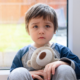 opioid crisis child/youth victims services grants; sad child holding teddy bear in front of window