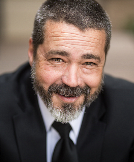 John Etchemendy newsmaker headshot; smiling bearded man in suit