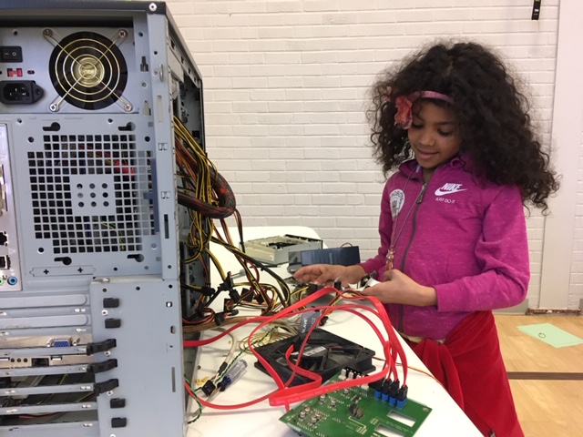 South Dakota: Little girl dressed in pink holds wiring from panel.