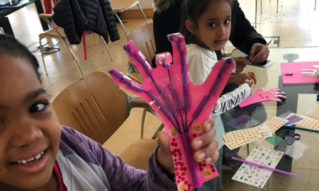 STEM: Little boy holds up pink hand-shaped thing with wires coming out of it.