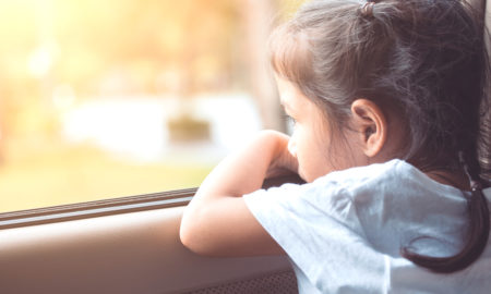 foster care: Little girl sitting in the car and looking out from the car window