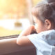 foster care: Little girl sitting in the car and looking out from the car window