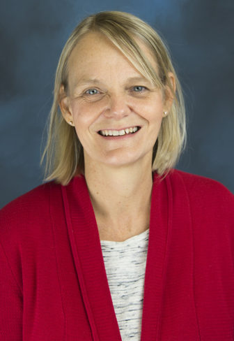 foster care: Kim Skobba (headshot), smiling woman with short blond hair, earrings, red jacket, gray and white top.
