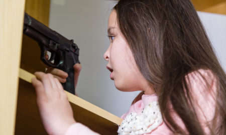 gun safety: Young child finds pistol in cupboard, gun control concept