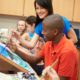 arts education program grants: teacher teaching students painting skills in classroom