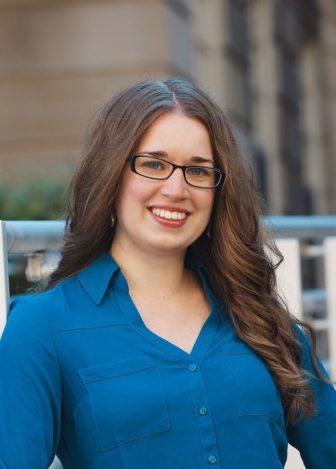  homelessness: Amanda Miller (headshot), housing and homelessness program manager at Institute for Innovation & Implementation, smiling woman with long brown hair, glasses, blue shirt 