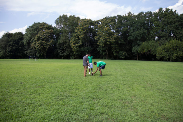 dog training: Distant view of adult, 2 boys in green shirts, tiny dog