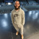 theater: Smiling young man in gray Nike sweats stands on theater stage.