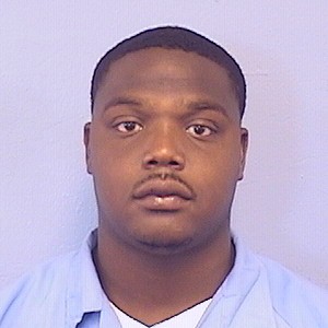 guns: Mug shot of unsmiling young man with light mustache, beard in light blue shirt with white undershirt