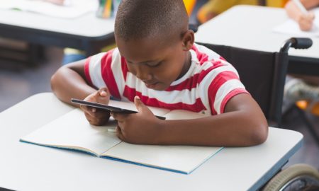 beyond suspensions report; young disable black student working on tablet at desk