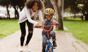 underserved community child welfare program grants; young mother teaching child to ride bike