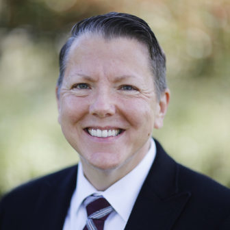 Homeless: Ames Simmons (headshot), Equality NC’s policy director, smiling man with graying short hair, dark jacket, white shirt, striped dark tie.