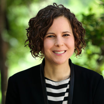 record clearing: Brett M. Merfish (headshot), director of youth justice at Texas Appleseed, smiling woman with short brown curly hair, black blazer, black and white top.