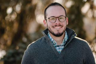 Jonah DeChants (headshot), postdoctoral fellow at Colorado State University, smiling man with short brown hair, beard, mustache, gray fleece jacket over checked shirt. 