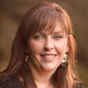 foster care: Kerri Kearney (headshot), associate professor in higher education, student affairs at Oklahoma State University, smiling woman with long red hair, earrings, pink top, black jacket