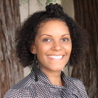 couch hopping: Stacey Ault (headshot), assistant professor in Division of Social Work at Sacramento State University, smiling woman with brown hair standing against tree wearing earrings, black and white checked shirt with big bow.