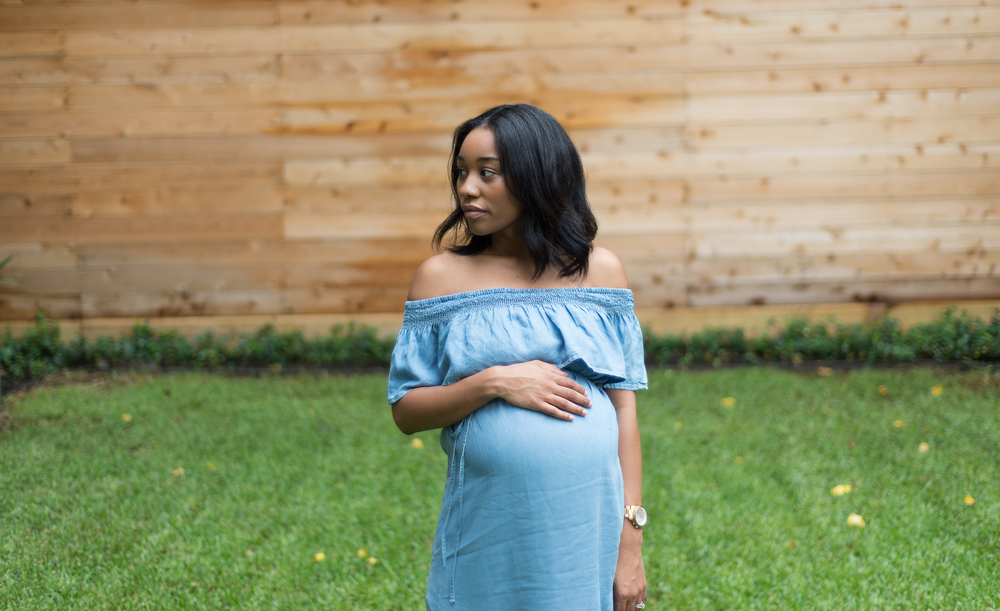 homelessness: Pregnant woman in backyard looking left.