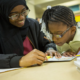 refugee community support grants; mother in hijab teaching child tor read