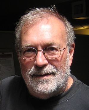 California: Mike Males (headshot), senior research fellow for the Center on Juvenile and Criminal Justice, serious-looking man with thinning gray hair, beard, mustache, wearing wire-frame glasses, black T-shirt.
