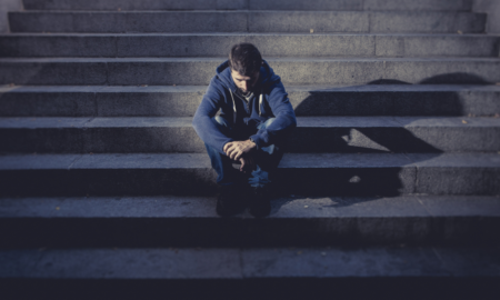 death rates due to suicide, homicide among youth aged 10-24 report; young depressed male looking sad on urban steps
