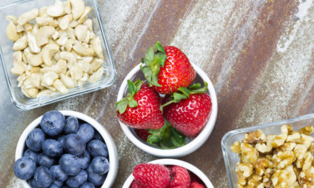 snacks: Healthy snack foods with small bowls of raspberries, blueberries, strawberries, cashews and walnuts