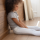 Adults Health Problems Attributable to Adverse Childhood Experiences report; young, sad black girl sitting on floor