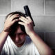 gun safety: Male teen with hands on head holding handgun