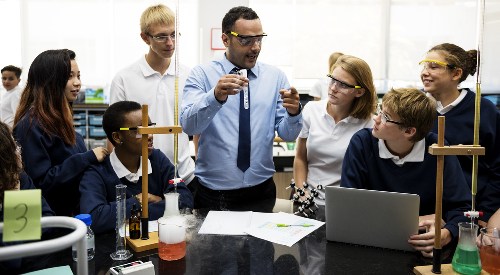 teacher support, learner-centered environment, academic improvement: male science teacher showing students test tube