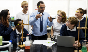 teacher support, learner-centered environment, academic improvement: male science teacher showing students test tube