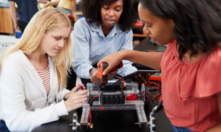 STEM education grants; female students and teacher work on tech project in classroom